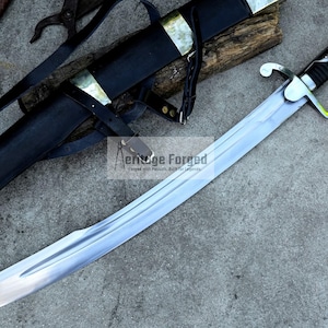 May include: A curved, silver-bladed sword with a black handle and guard, resting on a gray surface. The sword is accompanied by a black sheath with brass accents and leather straps. The text "Aenuge Forged" is visible.
