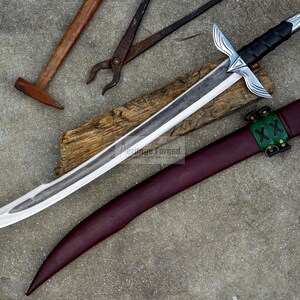 May include: A handcrafted sword with a silver blade and black handle, resting on a wooden plank. The sword is accompanied by a burgundy leather sheath with green accents. Blacksmith tools, including a hammer and tongs, are visible.