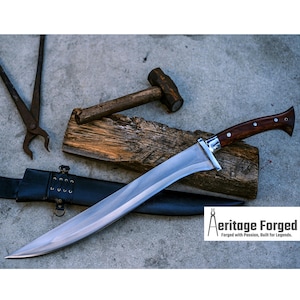 Könnte beinhalten: Eine lange, gebogene, silberne Klinge mit einem braunen Holzgriff. Die Klinge ist scharf und hat eine leichte Krümmung. Der Griff hat ein dekoratives Design. Die Klinge liegt auf einem Stück Holz. Der Text "Heritage Forged" ist in der unteren rechten Ecke des Bildes sichtbar. "Geschmiedet mit Leidenschaft, gebaut für Legenden."