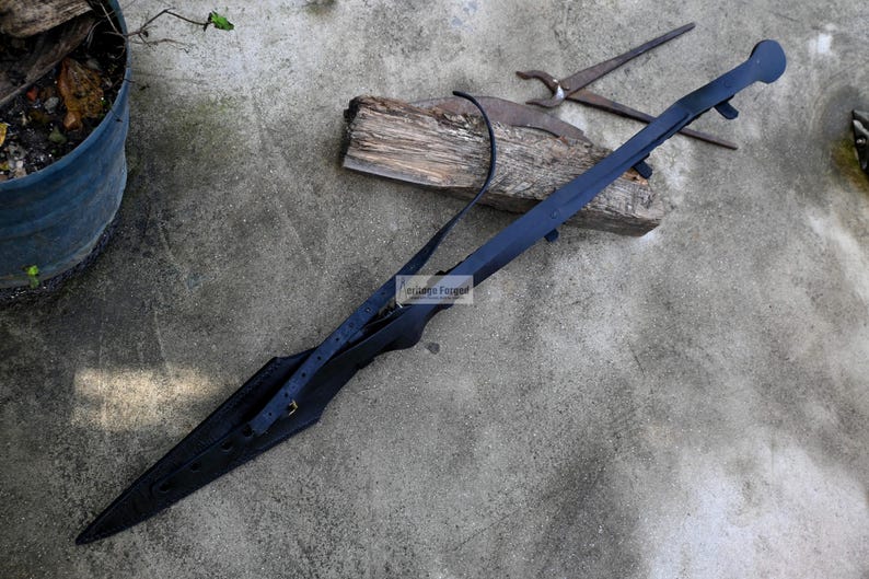 Puede incluir: Una vaina de cuero negro con una hoja larga y puntiaguda. La vaina est&aacute; asegurada con una correa y una hebilla. La hoja est&aacute; hecha de metal y tiene una punta afilada.