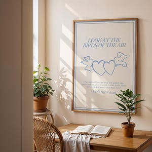 May include: A framed print with a blue and white illustration of two hearts and a bird. The text on the print reads "Look at the birds of the air. They neither sow nor reap nor gather into barns, and yet your heavenly Father feeds them. Are you not of more value than they? Matthew 6:26"