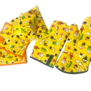 May include: Set of four yellow oven mitts and pot holders with a sushi and Japanese food print. The mitts and pot holders have a green, orange, and black trim.