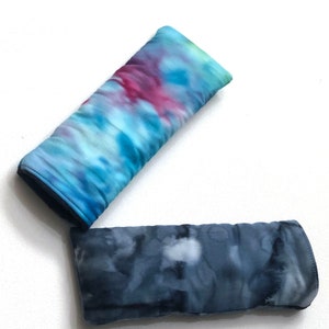 May include: Two tie-dye fabric eye pillows. One is blue, green, and pink. The other is a darker blue with white accents.