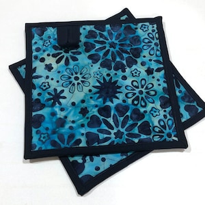 May include: Two blue and black floral patterned pot holders with a black border.
