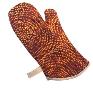 May include: A red and orange oven mitt with a white trim and a white strap. The mitt has a circular pattern of small dots.