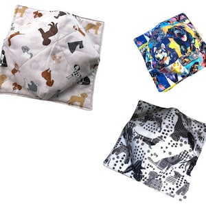 May include: Three different fabric bowl cozies. One is white with a brown, black, and gray dog print. One is white with a black and white geometric pattern. One is blue with a colorful dog print.