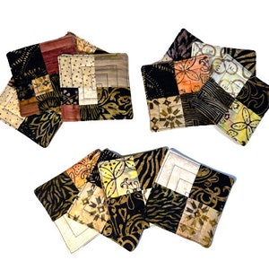 May include: Set of six square fabric coasters with a patchwork design. The coasters feature a variety of colors and patterns, including black, brown, beige, and orange. The coasters are made of quilted fabric and have a soft, textured surface.