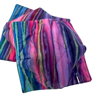 May include: Two quilted fabric hot pads with a colorful striped pattern in shades of pink, purple, blue, and green.