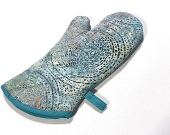 Manopla de horno acolchada de tela batik con estampado de remolinos azules y opción de pestaña para colgar.