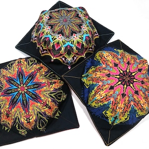 May include: Three black fabric bowl covers with colorful mandala designs. The covers are folded and arranged on a white background.