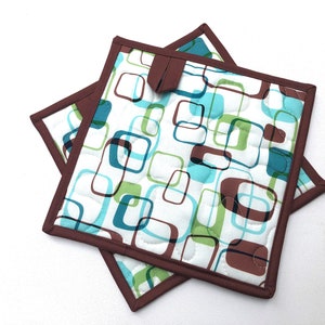 May include: Two brown and white quilted pot holders with a geometric pattern of teal, green, and brown squares.