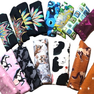 May include: A collection of 14 colorful eye pillows with various patterns, including stars, cats, horses, and abstract designs. The pillows are made of fabric and are rectangular in shape.