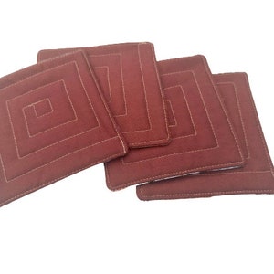 May include: Set of four brown quilted fabric coasters with a square design. Each coaster has a white stitched border and a square pattern in the center.