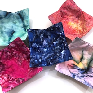 May include: Five fabric bowls in various colors and patterns. The bowls are made of a soft, quilted fabric and are perfect for holding small items like jewelry, keys, or snacks.