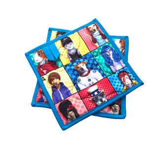 May include: Two blue quilted pot holders with a colorful patchwork design featuring various animals wearing costumes. The animals include a dog, a cat, a guinea pig, and a rabbit.