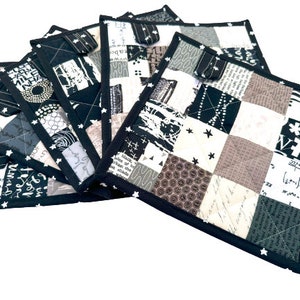 May include: Set of five black and white patchwork fabric pot holders with a black trim and white stars. The pot holders are made of different fabrics with various patterns, including black and white stripes, polka dots, and a script pattern.
