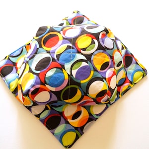 May include: A colorful bowl cozy with a black background and a pattern of overlapping circles in various colors, including red, yellow, blue, green, and white.