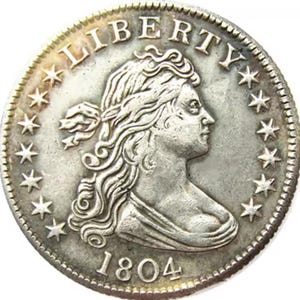 Könnte beinhalten: Eine silberne US-amerikanische Halbdolar-Münze mit der Aufschrift "LIBERTY" und dreizehn Sternen am Rand. Die Münze zeigt ein Brustbild von Liberty, das nach rechts blickt, mit dem Datum "1804" darunter.