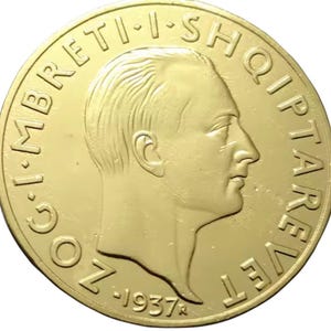 Peut inclure: Une pièce de monnaie dorée avec le profil d'un homme, entourée de texte en cercle. La pièce porte la date de 1937. Le design est détaillé et le fond est uni. Les détails de la pièce sont bien définis.