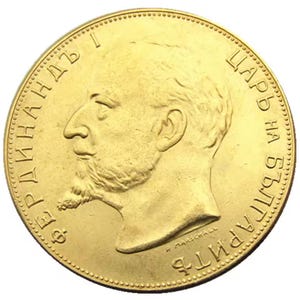 May include: A gold coin featuring a profile of a man with a mustache and beard, surrounded by text. The coin has a detailed edge and a shiny, reflective surface. The text includes the name "Фердинандъ I" and "Царь на Българитѣ".