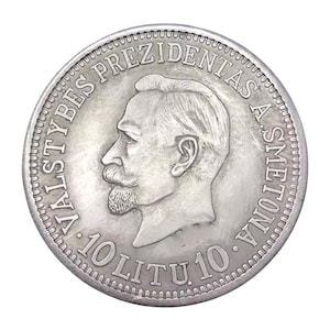 Puede incluir: Una moneda de plata con el perfil de un hombre con bigote y barba. La moneda tiene el texto "VALSTYBES PREZIDENTAS A. SMETONA" y "10 LITU 10" alrededor de los bordes.