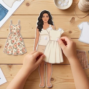 Può includere: Una bambola di carta con una varietà di opzioni di abbigliamento, tra cui un vestito floreale, una maglietta bianca e una gonna. La bambola viene vestita con un vestito color crema. La scena è ambientata su una superficie di legno.