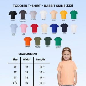 Op de afbeelding: Een perzikkleurig peuter-T-shirt van Rabbit Skins, maat 5/6, met een breedte van 38 cm en een lengte van 47 cm. De afbeelding toont ook een verscheidenheid aan T-shirtkleuren, waaronder zwart, wit en rood.