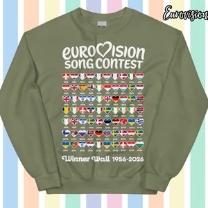 以下が含まれることがあります： オリーブグリーンのスウェットシャツには、白い文字で「EUROVISION SONG CONTEST」と書かれています。下には、1956年から2026年までの勝者を象徴するハート型の旗があります。「Winner Wall 1956-2026」の文字が下部に印刷されています。