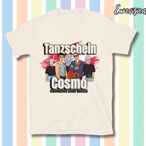 Könnte beinhalten: Cremefarbenes T-Shirt mit einer Grafik einer Band und dem Text "Tanzschein Cosmo Eurovision 2025 Vienna". Die Bandmitglieder sind im Cartoon-Stil dargestellt, mit einem Löwen und einer Gitarre. Das Shirt hat kurze Ärmel.