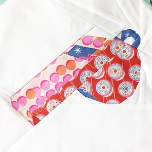 May include: A red, white, and blue fabric scrap with a pattern of spools of thread. The spools have text that reads "Cotton", "Twice Wound", "100%", "50", "Tightly Wound", "Sew with Love", and "15423".