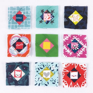 Könnte beinhalten: Neun bunte Stoffquadrate mit verschiedenen Mustern und Designs. Jedes Quadrat hat eine zentrale Diamantform mit einem kleineren Design im Inneren. Die Designs beinhalten ein Herz, einen Stern, eine Blume, einen Hund, eine Katze und ein geometrisches Muster. Die Quadrate sind in drei Reihen zu je drei angeordnet.