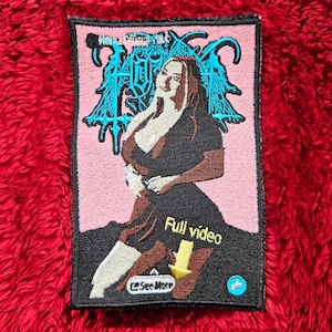 May include: A pink and black embroidered patch with a woman in a black dress and a blue and black logo that says "Horna" above her. The text "Full video" is below her with a yellow arrow pointing down. The text "25 Sec More" is below the arrow. A blue thumbs up icon is to the right of the arrow.