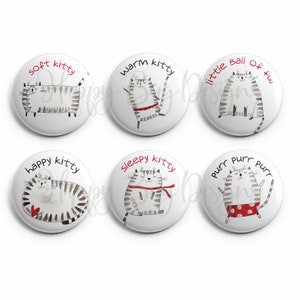 May include: Six round white buttons with black and white illustrations of cats. Each button has a different phrase on it, including "soft kitty", "warm kitty", "little ball of fur", "happy kitty", "sleepy kitty", and "purr purr purr".