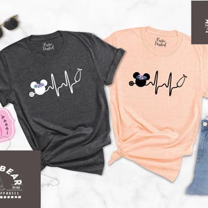 May include: Two t-shirts featuring a black and white graphic of a cartoon mouse wearing a flower crown and a stethoscope with a heartbeat line. The text "Ships Today" is visible in the image.