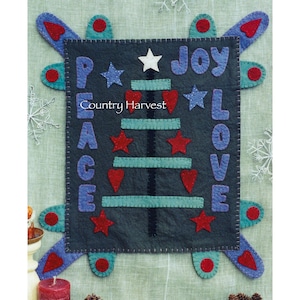 May include: A felt Christmas tree wall hanging with the words "Peace", "Joy", "Love" in blue lettering. The tree is decorated with red stars, red hearts, and a white star on top. The words "Country Harvest" are printed in white on a black banner.