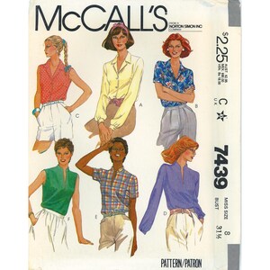 May include: A McCall's sewing pattern envelope, number 7439, featuring illustrations of six different shirt and blouse styles. The designs include sleeveless, short-sleeved, and long-sleeved options in various colors like red, yellow, blue, green, and purple.