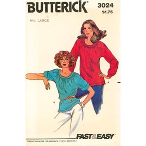 May include: Butterick sewing pattern 3024 for a top in size large. The illustration shows two variations: one in red with long sleeves and one in teal with short sleeves, both featuring a gathered round neckline and a relaxed fit. Text includes FAST & EASY.