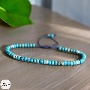 May include: A turquoise and silver beaded bracelet with a dark blue cord closure.