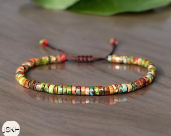 May include: A colorful beaded bracelet with a brown cord closure. The beads are small and round, and they are arranged in a random pattern. The bracelet is made of natural materials and has a rustic look.