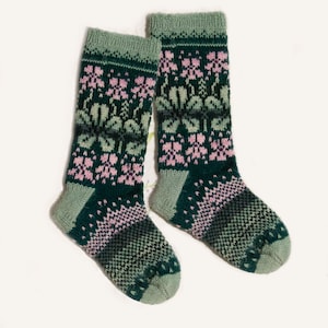 Può includere: Un paio di calzini di lana verde, rosa e bianco. I calzini hanno un motivo floreale.