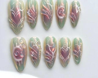 May include: A set of ten almond-shaped press-on nails featuring an iridescent light green and pink base. Each nail is decorated with raised white 3D gel line art, swirling patterns, heart motifs, and small clear gel droplets across the surface.