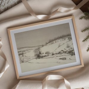 May include: A black and white drawing of a snowy landscape with a small village nestled in the hills. The drawing is framed in a light wood frame.
