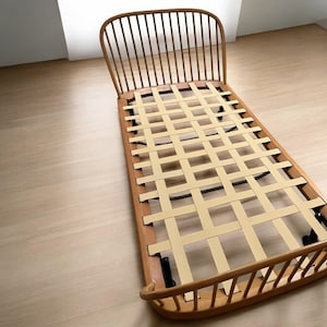May include: A wooden bed frame with a slatted headboard and a woven fabric base. The frame is made of natural wood and has a light brown finish.