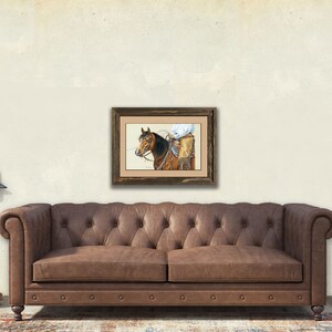 Peut inclure: Une peinture encadr&eacute;e &agrave; l'aquarelle repr&eacute;sentant un cow-boy &agrave; cheval, avec un cadre en bois marron. L'&oelig;uvre est affich&eacute;e au-dessus d'un canap&eacute; en cuir marron. La pi&egrave;ce a une esth&eacute;tique vintage, avec un lampadaire et une table d'appoint.