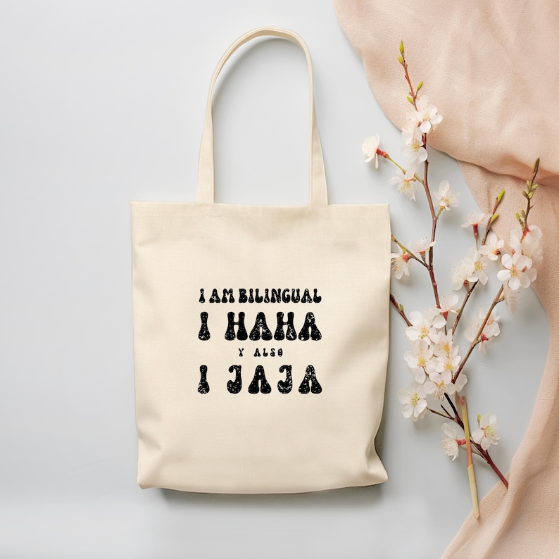 May include: A white canvas tote bag with black text that reads "I am bilingual I haha & also I jaja".