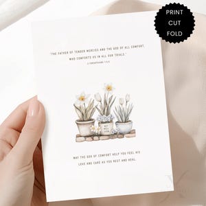 May include: A white greeting card featuring a watercolor illustration of three potted flowers. The text reads: The Father of tender mercies and the God of all comfort, who comforts us in all our trials. 2 Corinthians 1:3-4. May the God of comfort help you feel His love and care as you rest and heal.