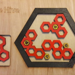 May include: The Hive board game with a hexagonal game board and red hexagonal tiles. The game board has a black border and the tiles are arranged in a honeycomb pattern. There are four yellow bee tokens on the board.