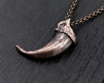 Colar com pingente de garra de lobo em bronze oxidado, símbolo da vida selvagem.