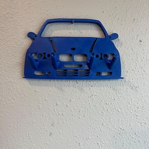 May include: A blue 3D printed car-shaped wall hook with five hooks on the front bumper.