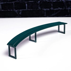 May include: A curved green bench with three legs on each side. The bench is made of wood and has a smooth finish.